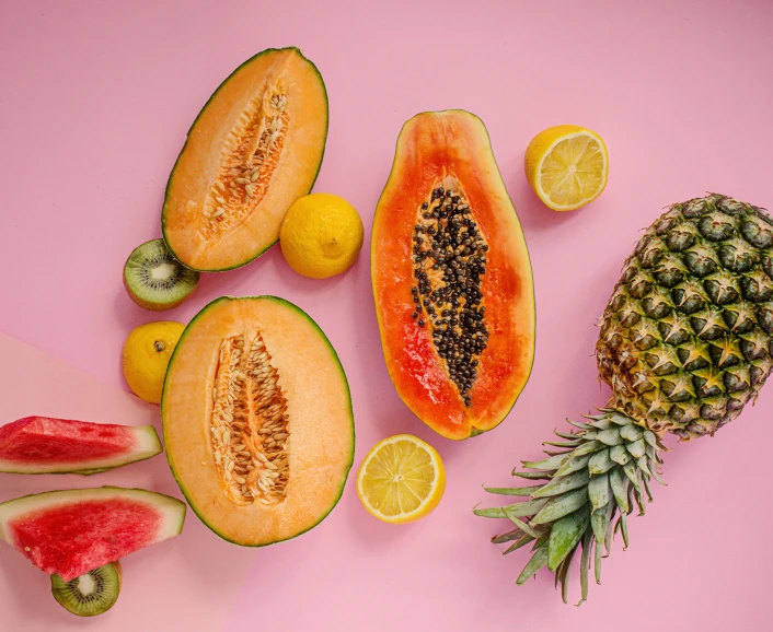 a bunch of fruits are lying on a pink surface