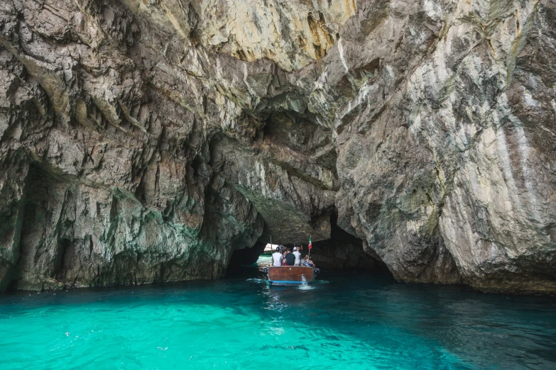 a boat in a cove, next to an enormous rock formation