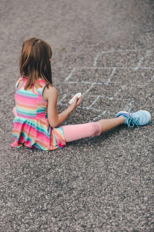 a  is sitting on the ground playing with chalk