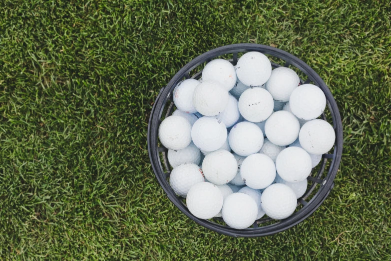 a basket full of white balls sitting in the grass