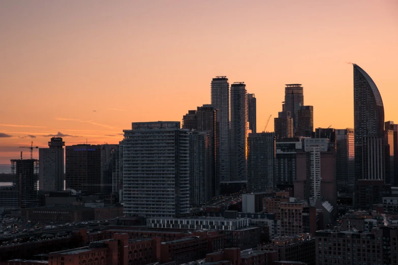 a bunch of skyscrs in an industrial city at sunset