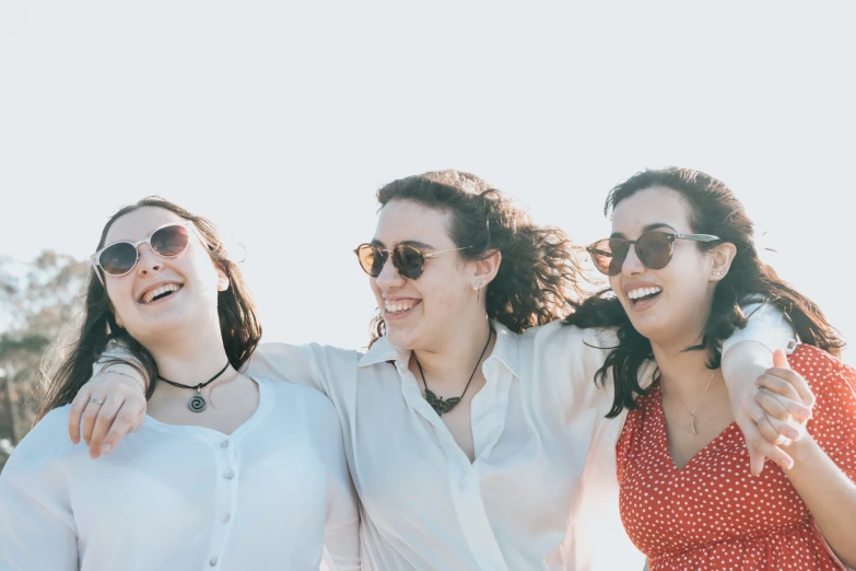 three woman wearing white shirts are smiling and laughing