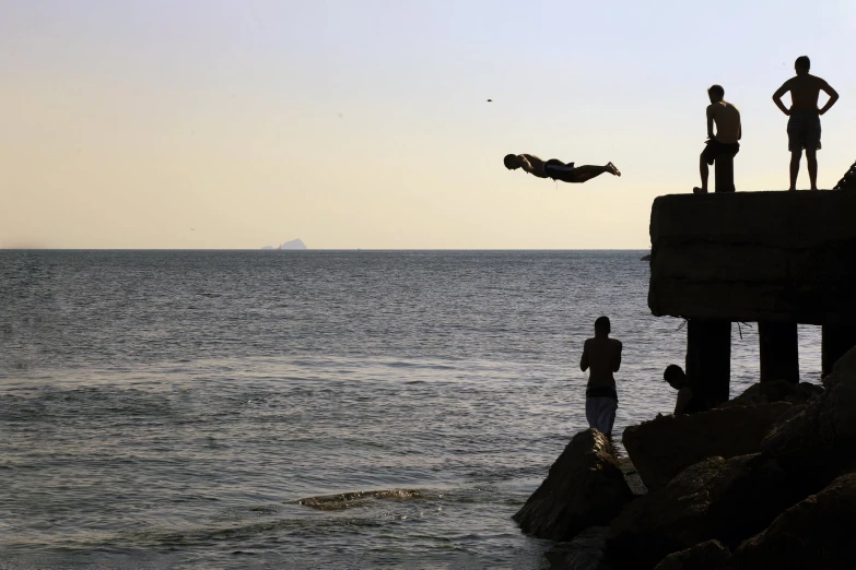 two people are on a cliff near the ocean