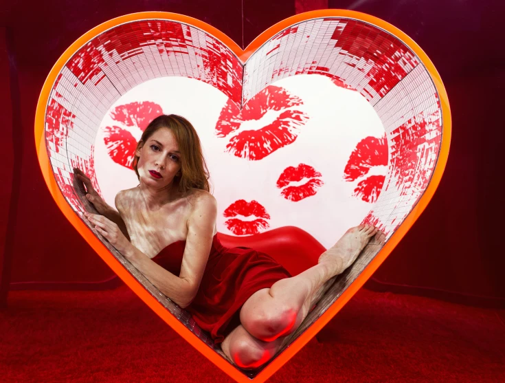 a woman sitting in front of a giant heart