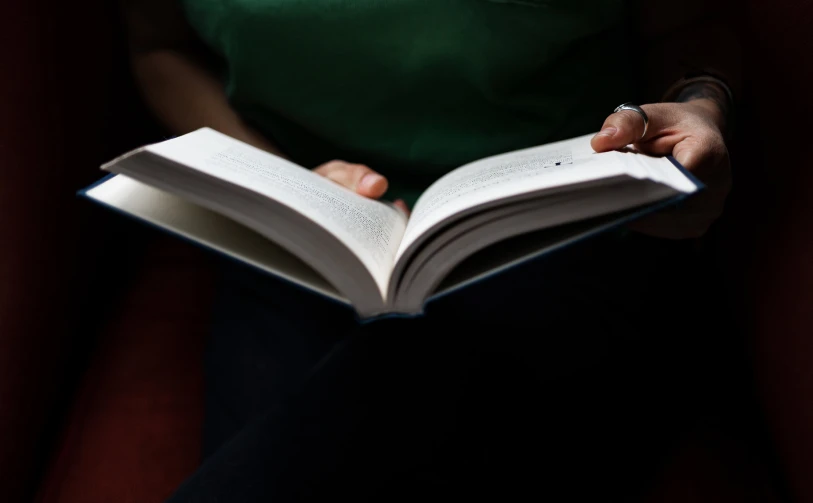 a woman reads a book while sitting in a chair