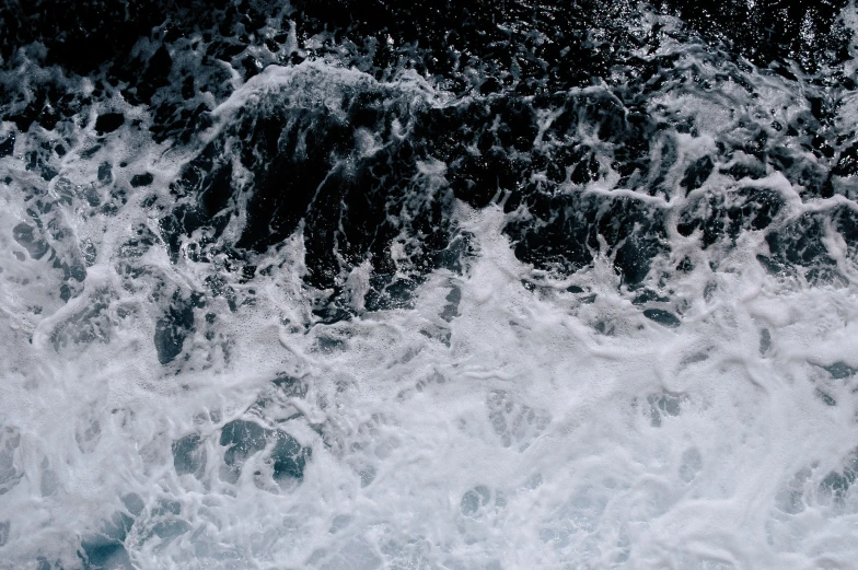 rough white foamy water next to a rock formation