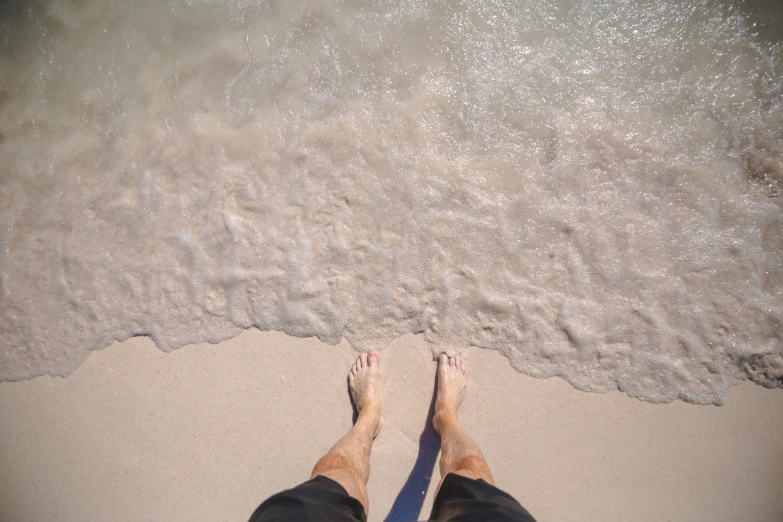 a person stands on the beach next to the water