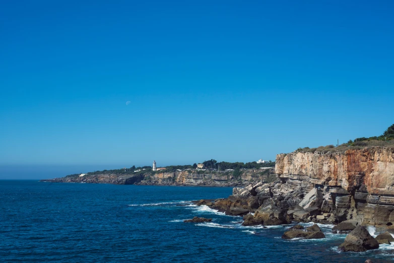 a clear, blue sky hangs over a rocky shoreline