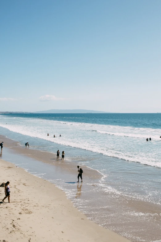 a beach filled with people walking along the shore