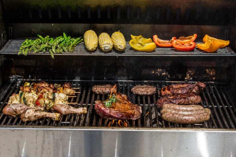 steaks and hamburgers cooking on an outside grill