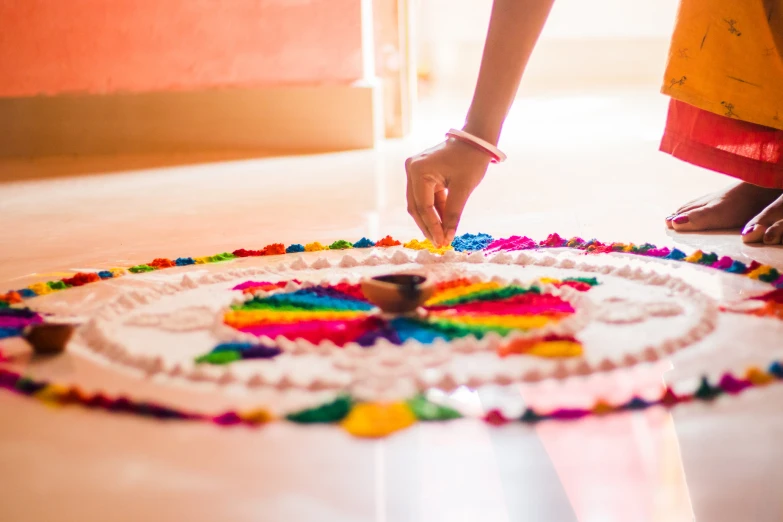 someone decorating a large colorful circular decorative piece