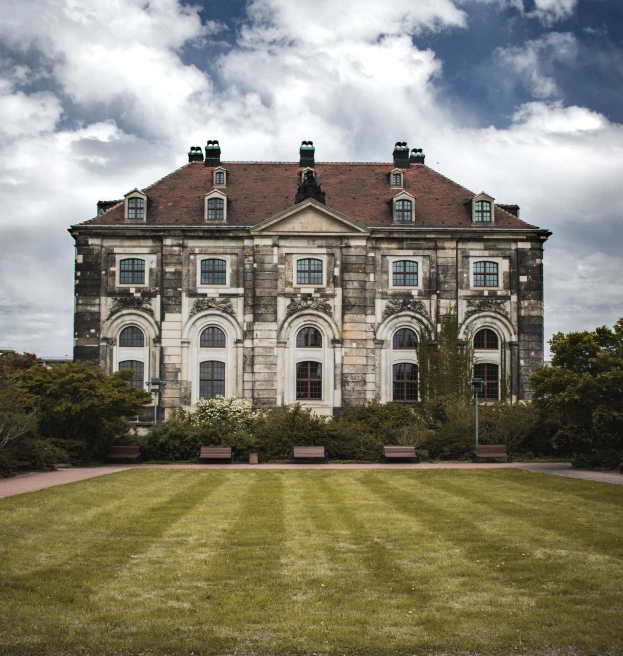 a very large, old building sits in the background with many plants