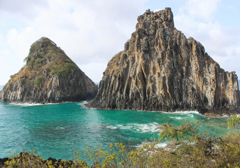 an ocean view of some rocks sticking out of the ocean