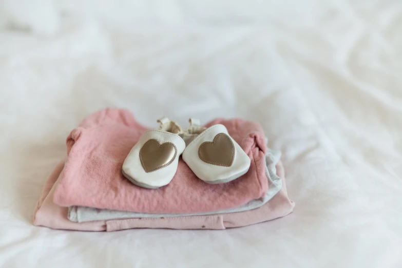 a pair of shoes with a pink blanket on a white bed