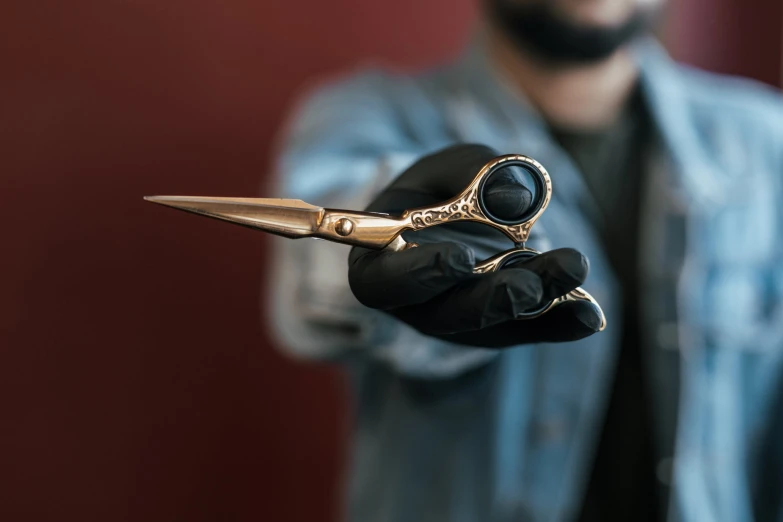 a person wearing black gloves holding scissors in their hands
