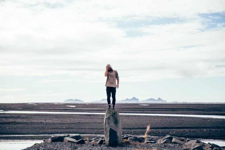 a woman stands on a large rock in a desert