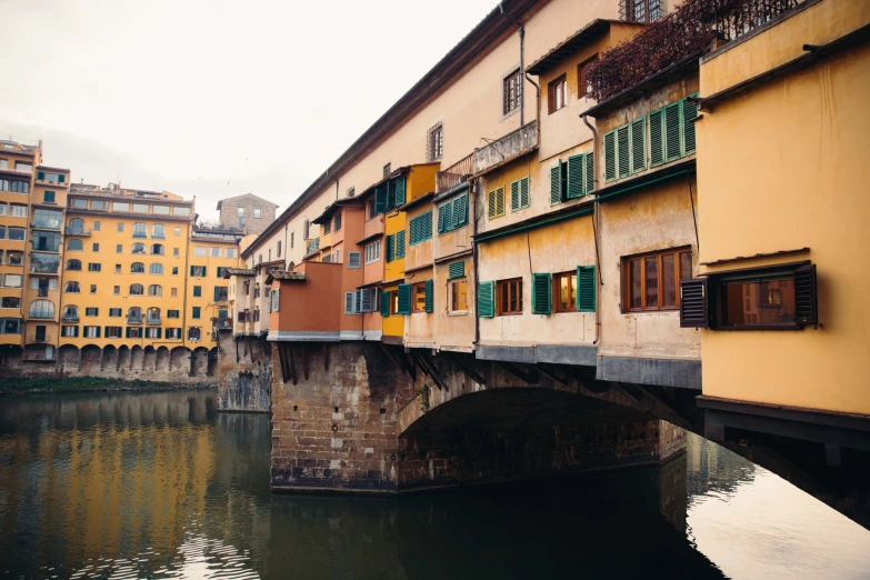 a narrow river running past some buildings with green shutters