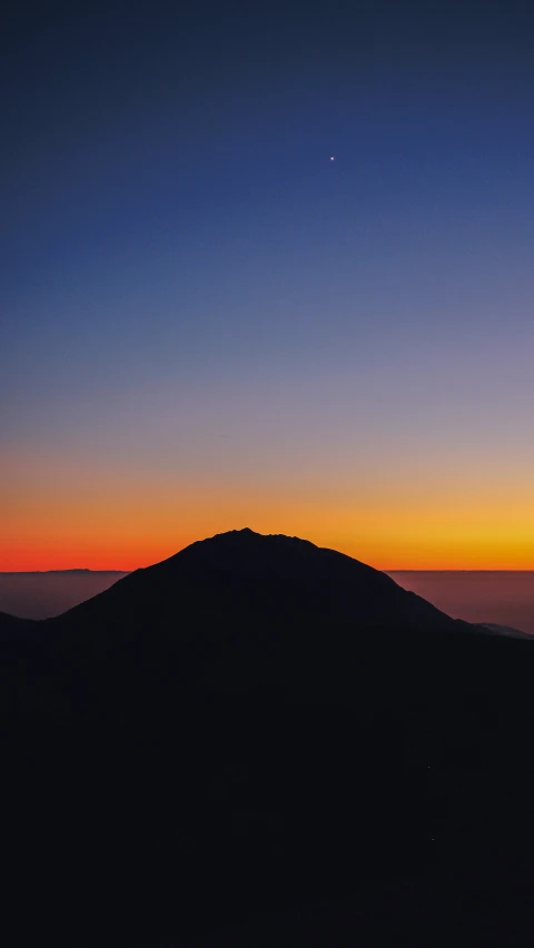 a hill on top of a mountain with the sun setting