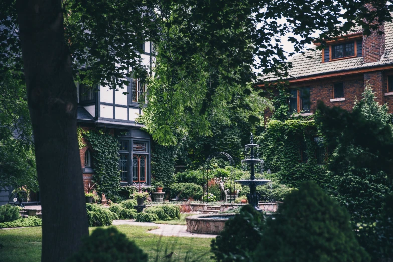 large home with trees, grass and fountain in front of it