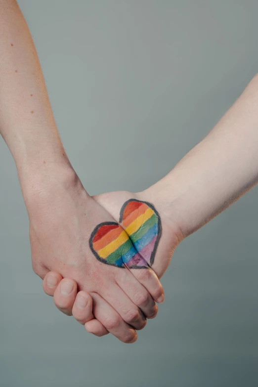 a person holding the hand of another person with a colorful heart tattoo