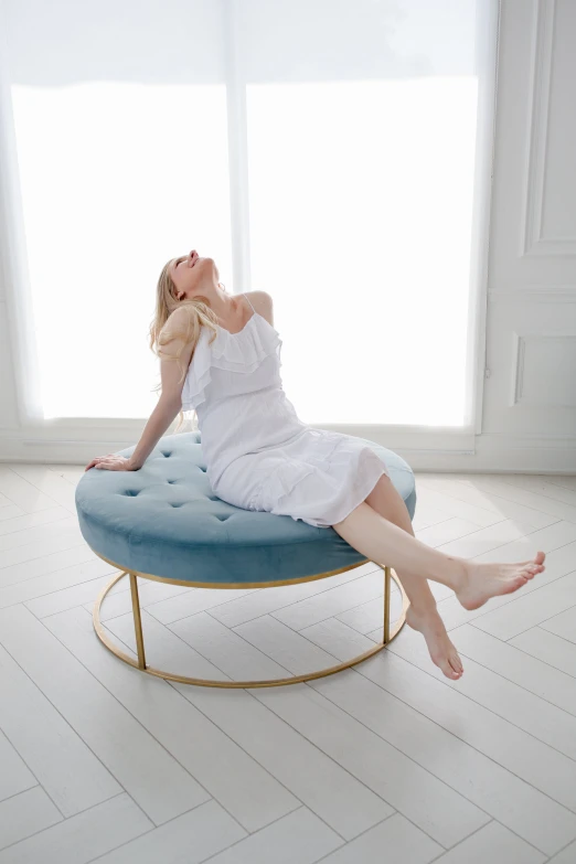 a beautiful young lady in a white dress laying on a blue bench