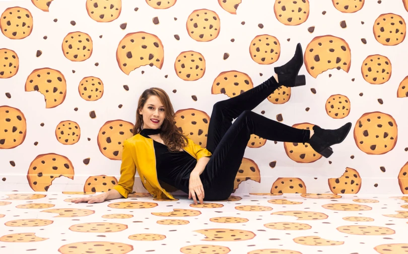 a woman with one leg on the floor while posing in front of a wall with cookies