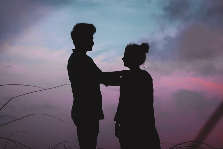 a silhouetted couple are standing with each other