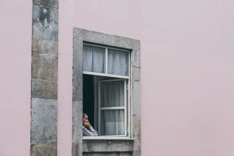 a woman is looking out of a window of an old apartment building
