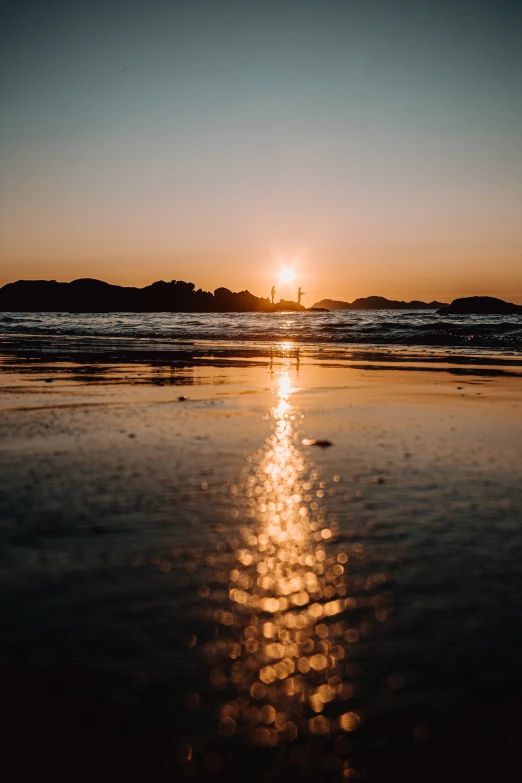 a beach has a line of sun reflecting on the sand