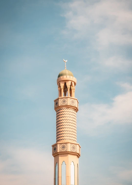 a tall tower with a cross on top against the blue sky