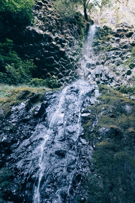 a small waterfall flowing over green grass covered land