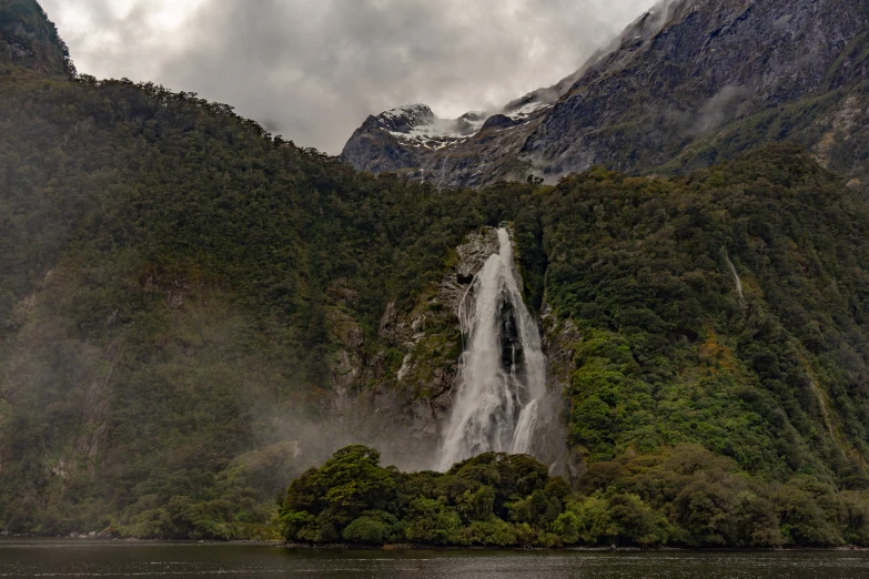 a waterfall with water falling into the ground near a forest