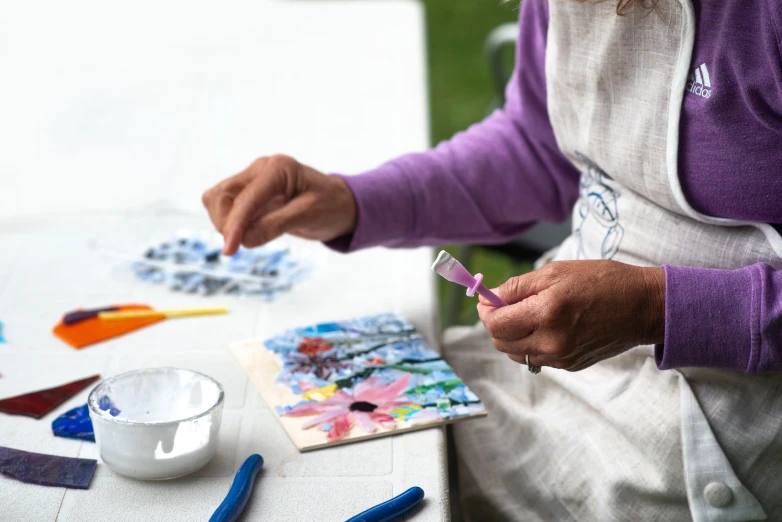 a woman sitting at a table making artwork