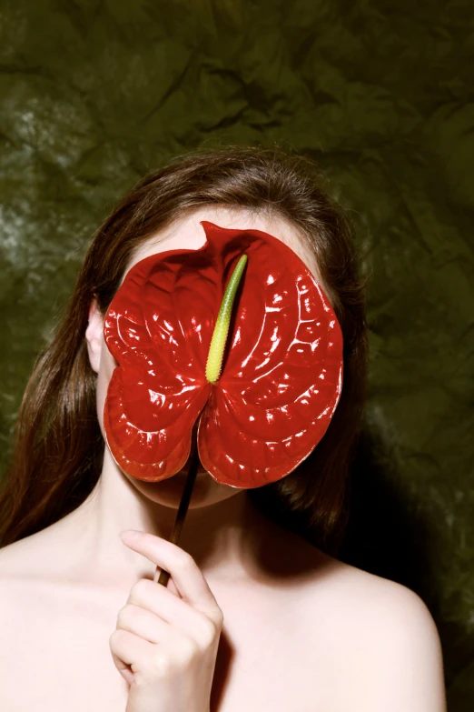 a woman holding a large red flower to her face