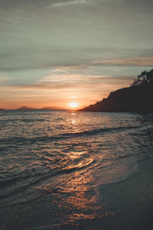 the sun rising over an island on the ocean