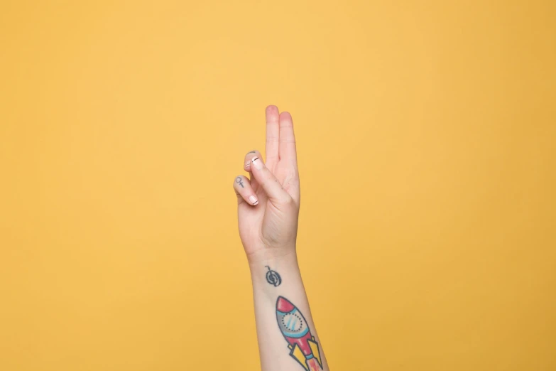 a hand with tattoos shows the letter u