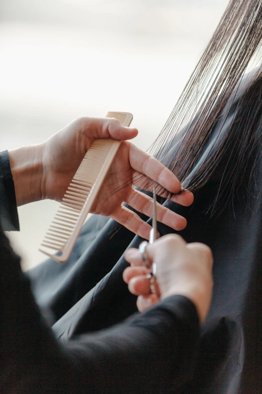 a woman holding up her hair comb and scissors