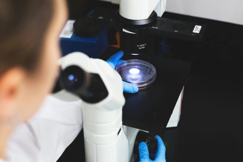 the image shows two labcoats with gloves on and a microscope