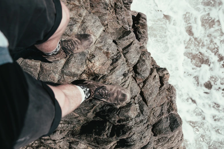 feet are up on a rocky shore near the ocean