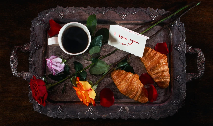 a plate with flowers and croissants next to a cup of coffee