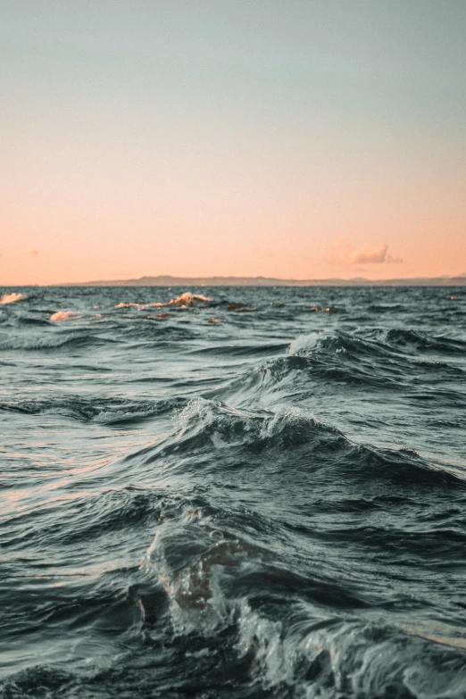 a boat in the ocean at sunset near a beach