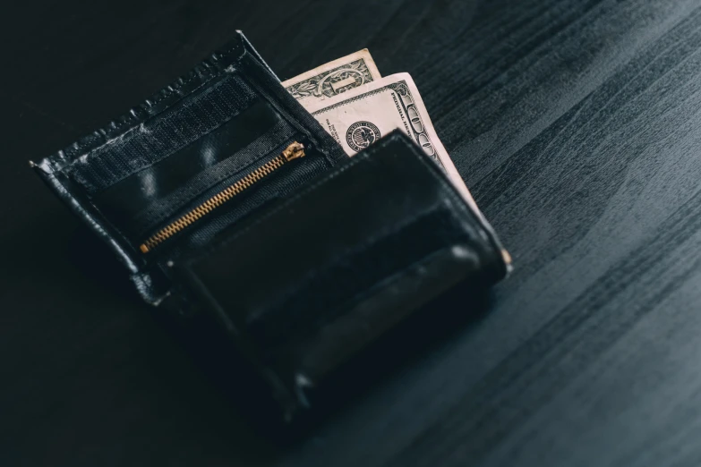 an empty wallet is sitting on top of cash