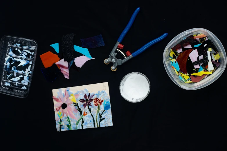 craft supplies lay next to a small white bowl with blue handles and scissors