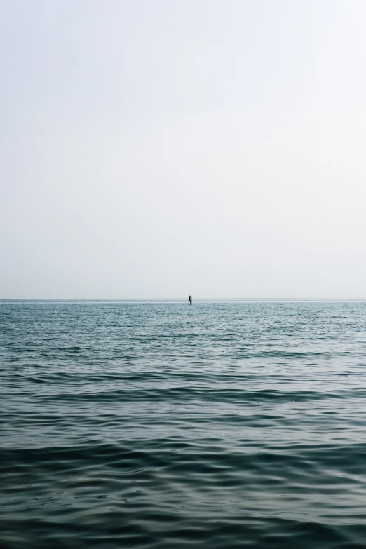 an ocean is shown with a lone boat out in the distance