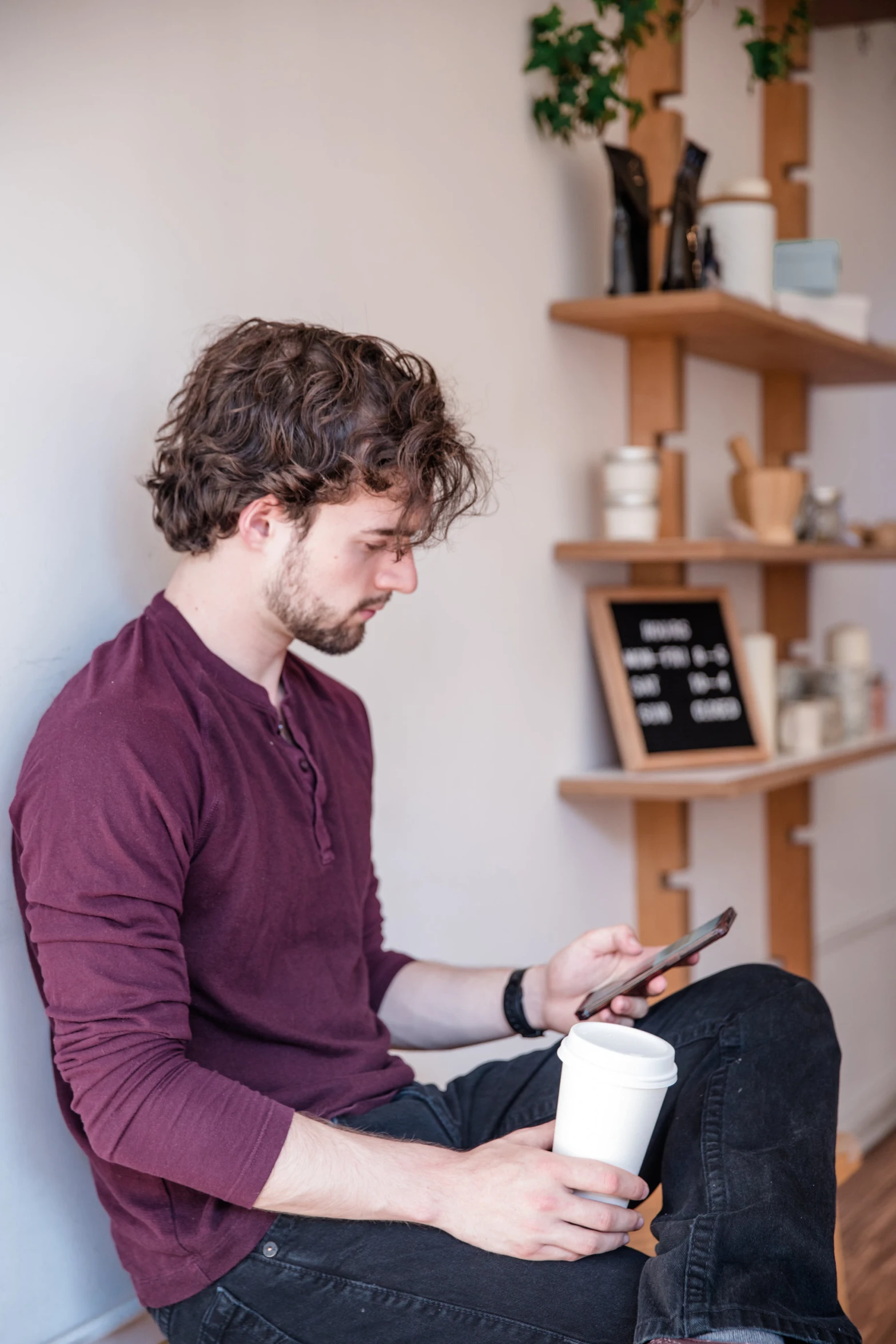 a man in red shirt and black jeans holding a cell phone