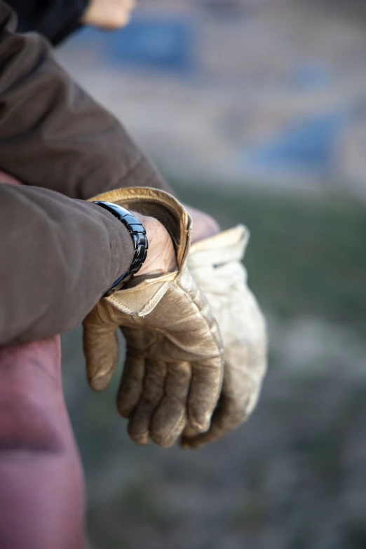 a close up of a person wearing large leather gloves