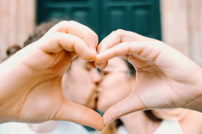 a person is holding their fingers out making a heart