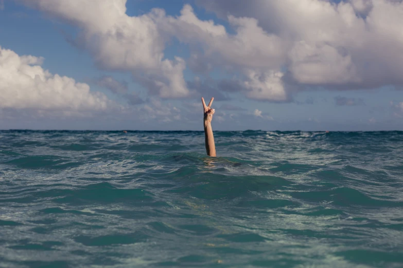 someone standing in the middle of the ocean, holding their hands up