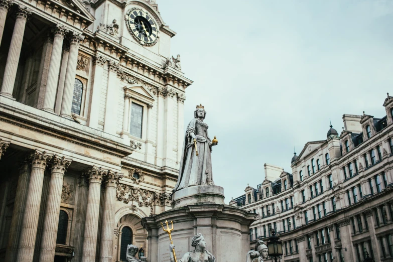 a tall statue sits in front of a clock tower