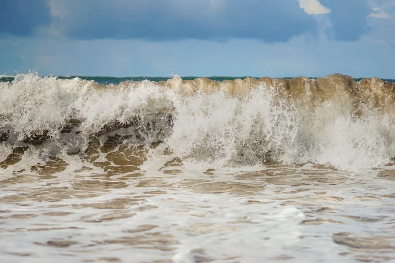 a large wave coming towards the beach and the shore